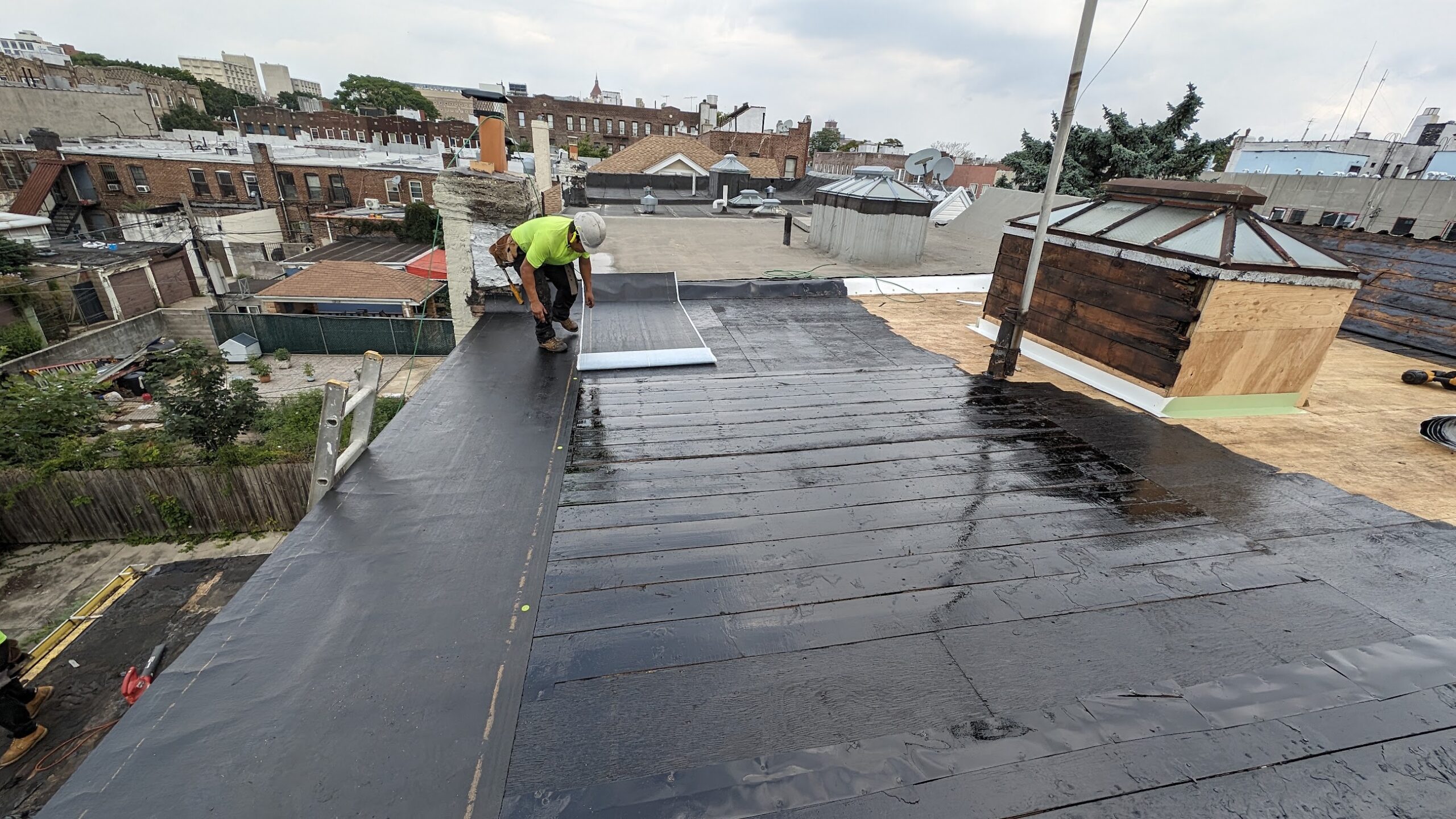 Worker installing low-slope roof membrane over repaired decking