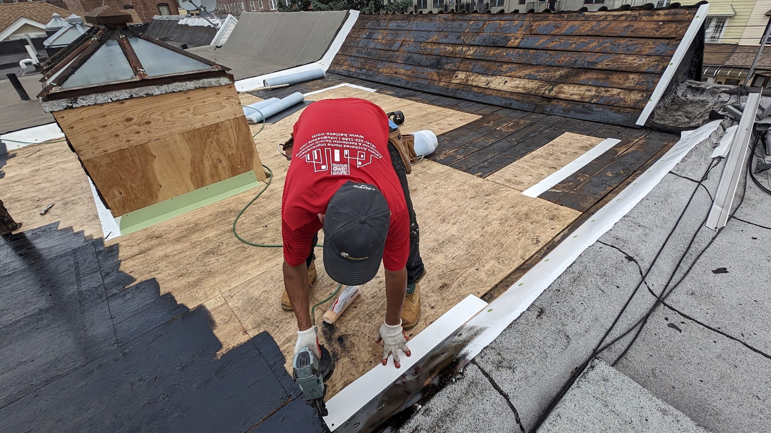 Kellets branded worker fastening edge metal beside a low-slope roof