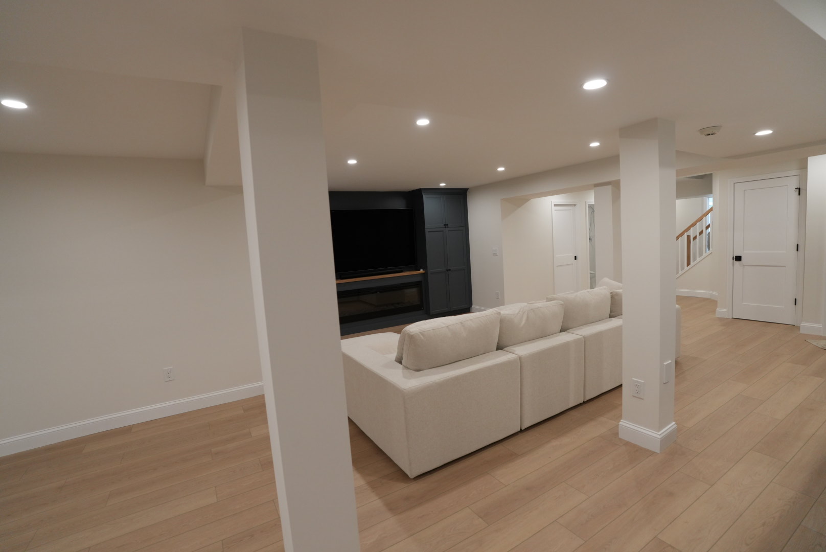 Finished Kellets basement showing columns, stair, doors and coordinated ceiling layout