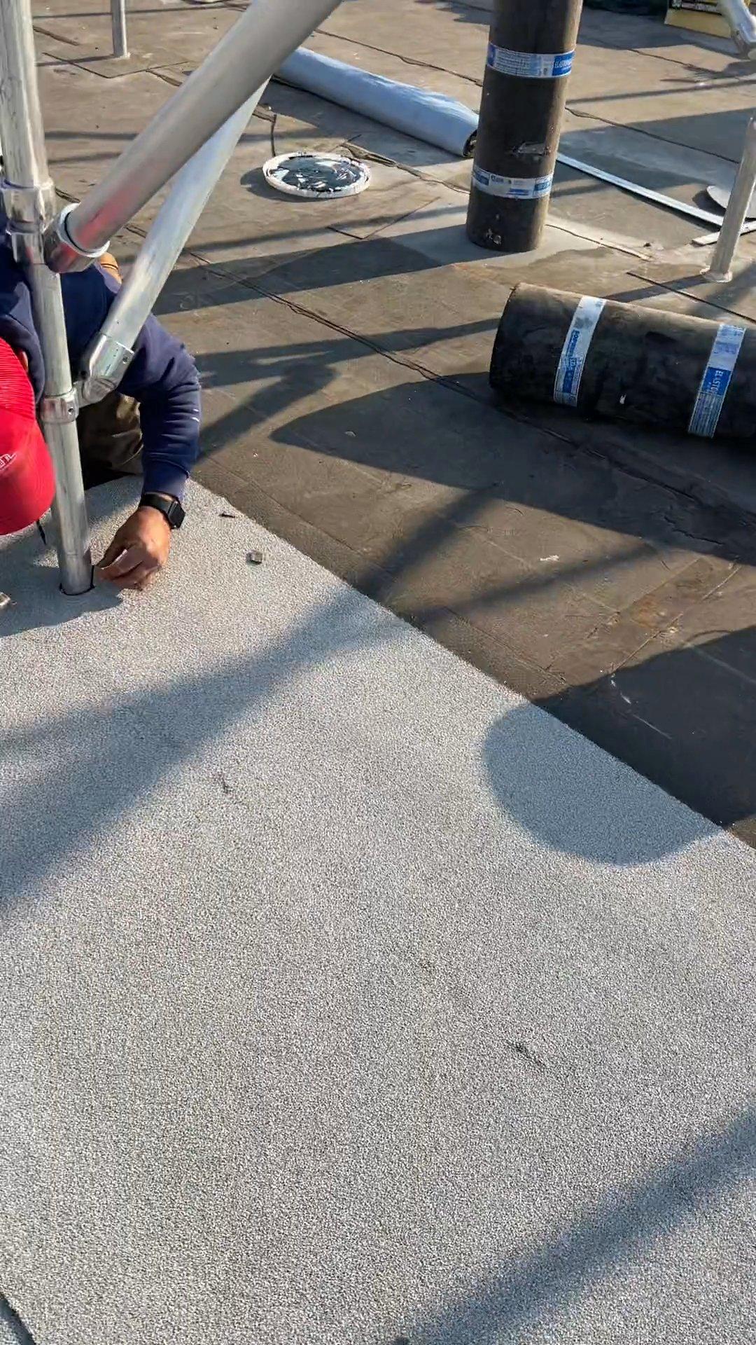 Kellets roofer aligning a SOPREMA cap sheet around a rooftop support