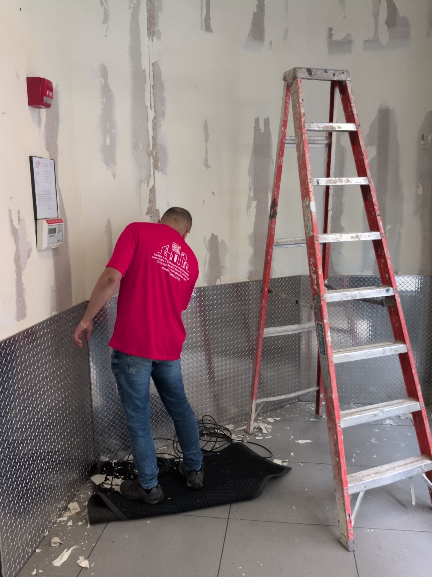Kellets team member installing diamond-plate wall protection in a Manhattan fitness facility