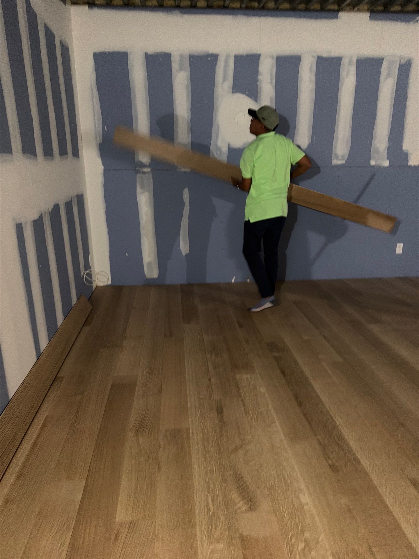 Kellets project worker carrying finish material through a room with newly prepared walls