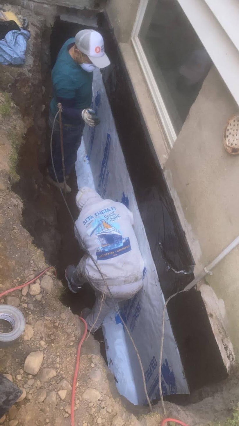 Two Kellets field team members working at an exposed foundation wall