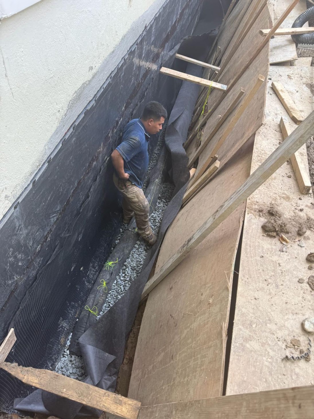 Kellets installer working beside an exterior foundation drainage assembly